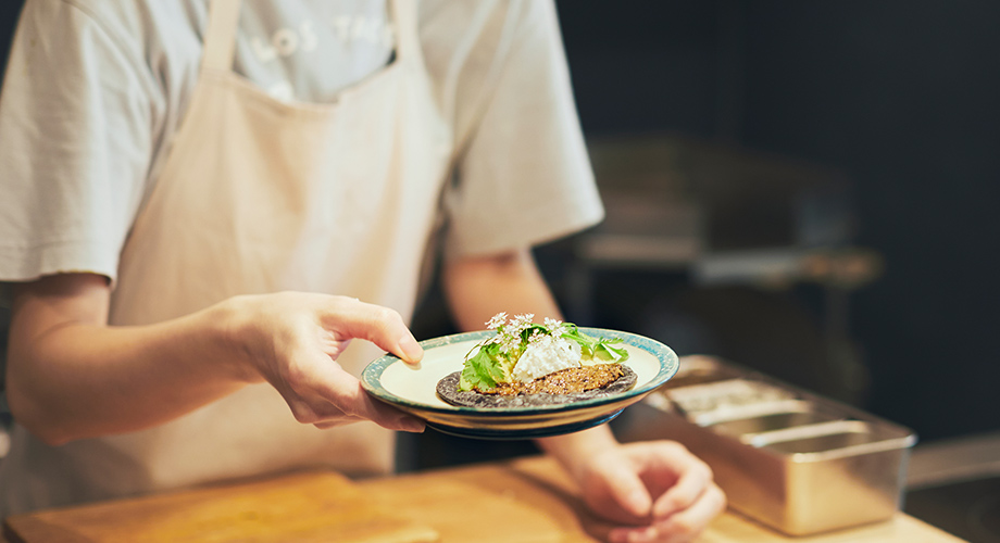 焦がしなすと山羊チーズを手に持つ店員